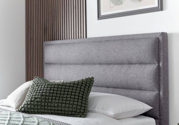 A luxurious contemporary ottoman bed frame with a modern horizontal padded headboard in grey fabric